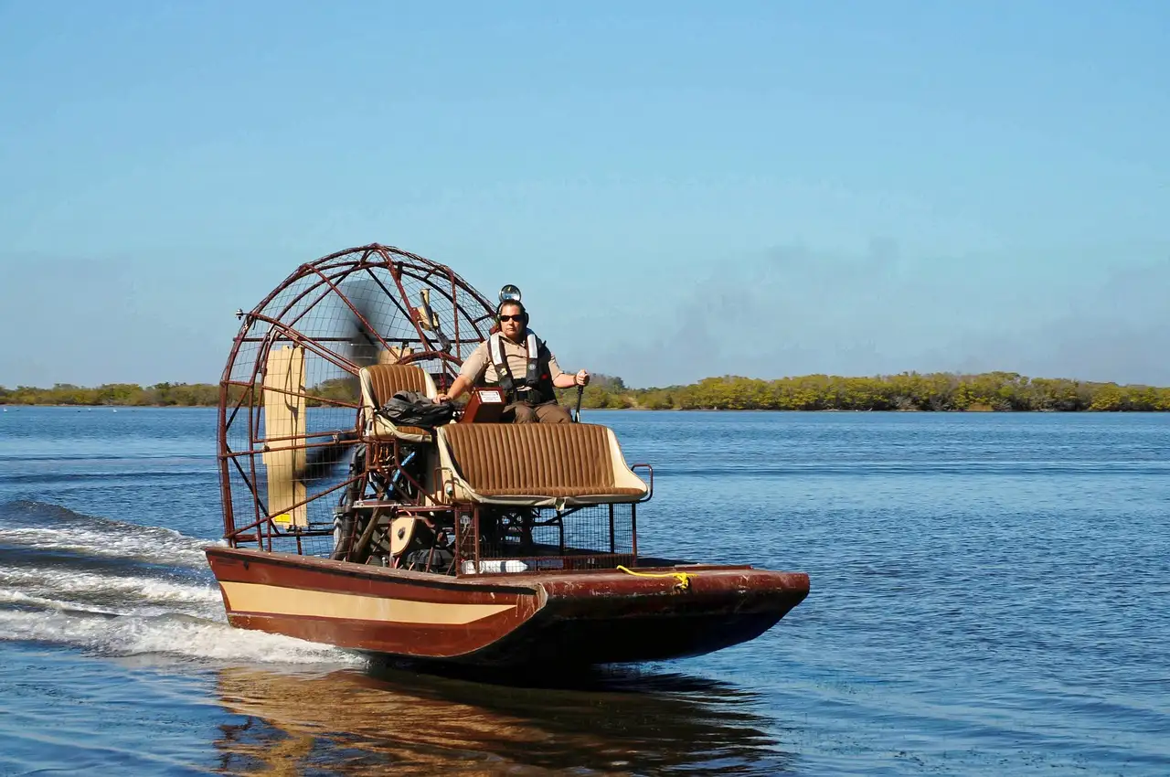 An airboat speeding across open water with mangroves on the horizon