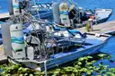 Airboats with fan cages docked among lily pads