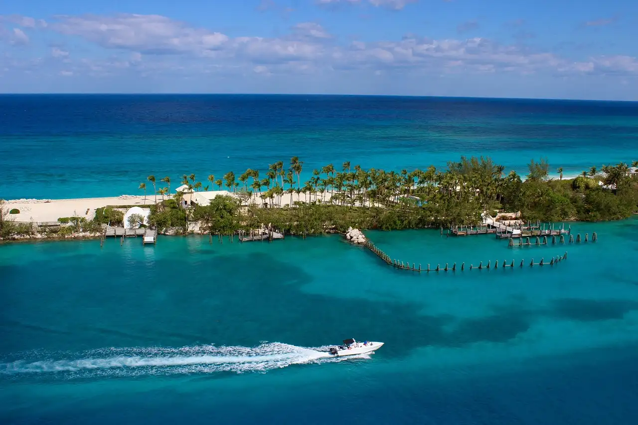 A speedboat crossing turquoise water along a Bahamas coastline