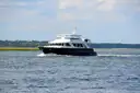 A black-hulled motor yacht underway on open water