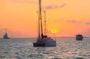 A catamaran at anchor at sunset with boats behind