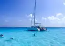 A catamaran anchored in turquoise water with snorkelers nearby