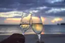 Two champagne glasses against a sunset sea
