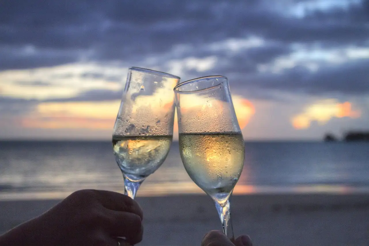 Two champagne glasses against a sunset sea