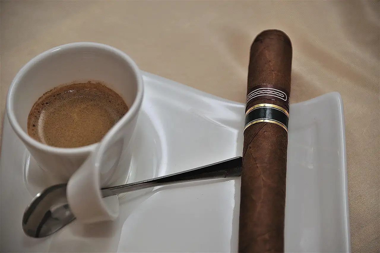 A cigar resting by a cup of coffee