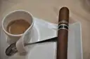 A cigar resting by a cup of coffee