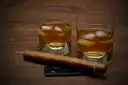 A cigar beside two glasses of dark rum