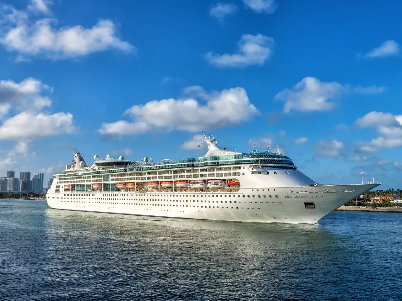 Cruise ship leaving Miami on blue water with the city skyline behind