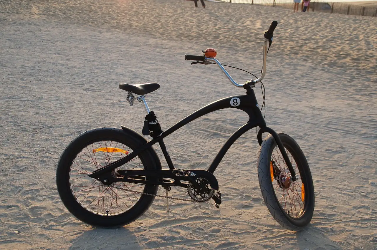 A black cruiser bicycle standing on beach sand