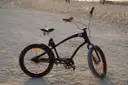 A black cruiser bicycle standing on beach sand