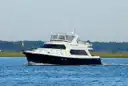 A dark-hulled motor yacht of about 50 feet cruising on calm water