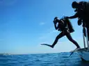 Divers stepping off the back of a dive boat into the sea