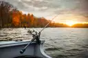 A fishing rod set in a holder on a boat rail at sunset