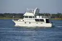 A white flybridge cruiser of about 40 feet underway on a calm river