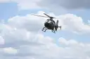 A helicopter flying past white clouds