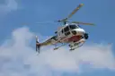A white helicopter banking against a blue sky
