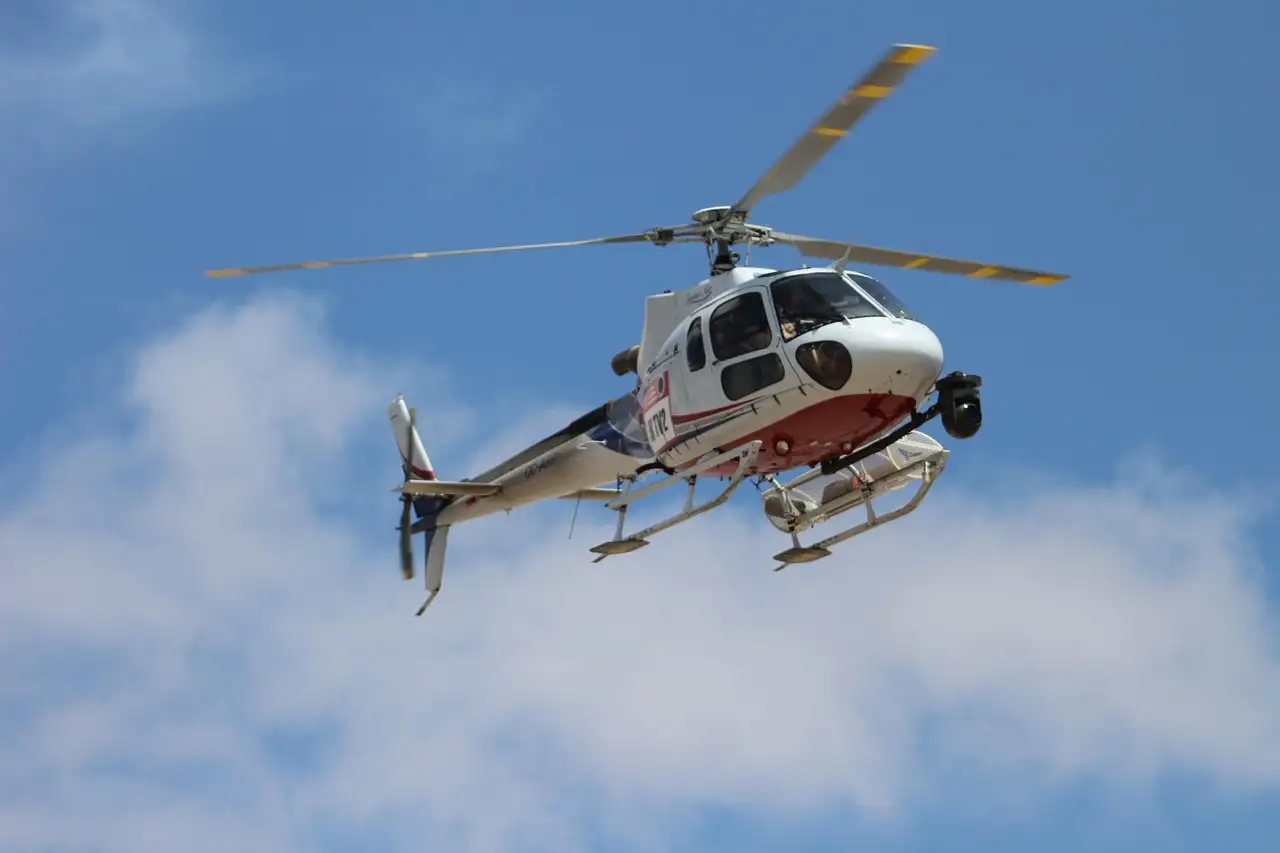 A white helicopter banking against a blue sky