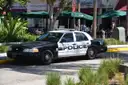 Police car parked on a South Beach street in front of cafe awnings