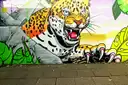 A street-art mural of a jaguar among leaves