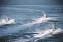 Jet skis leaving white wakes across the sea