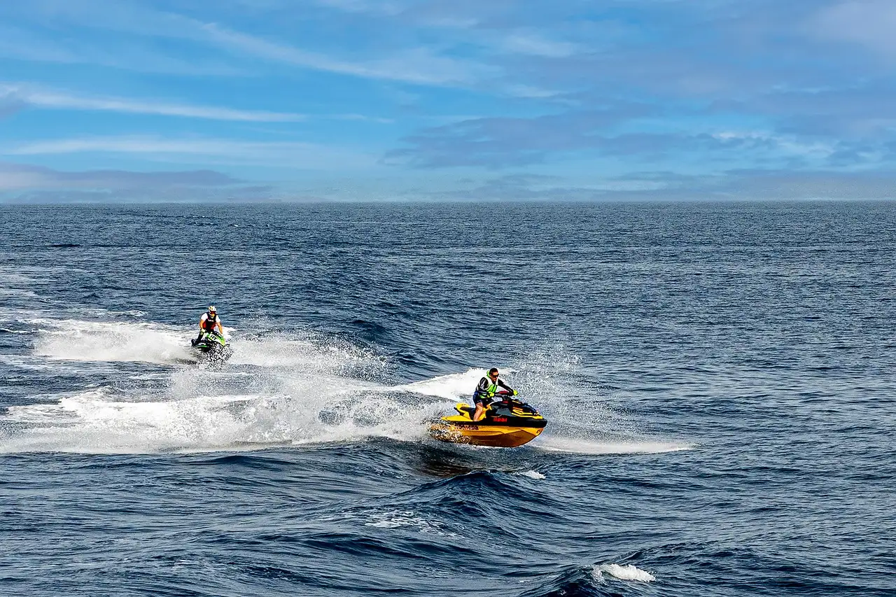 Two jet skis crossing the open sea under a blue sky