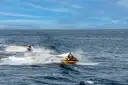Two jet skis crossing the open sea under a blue sky