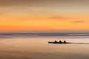 Kayakers in silhouette on calm water at sunset