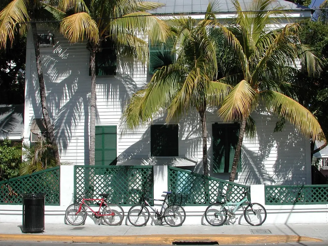 A historic Key West house behind palm trees, with bicycles parked out front