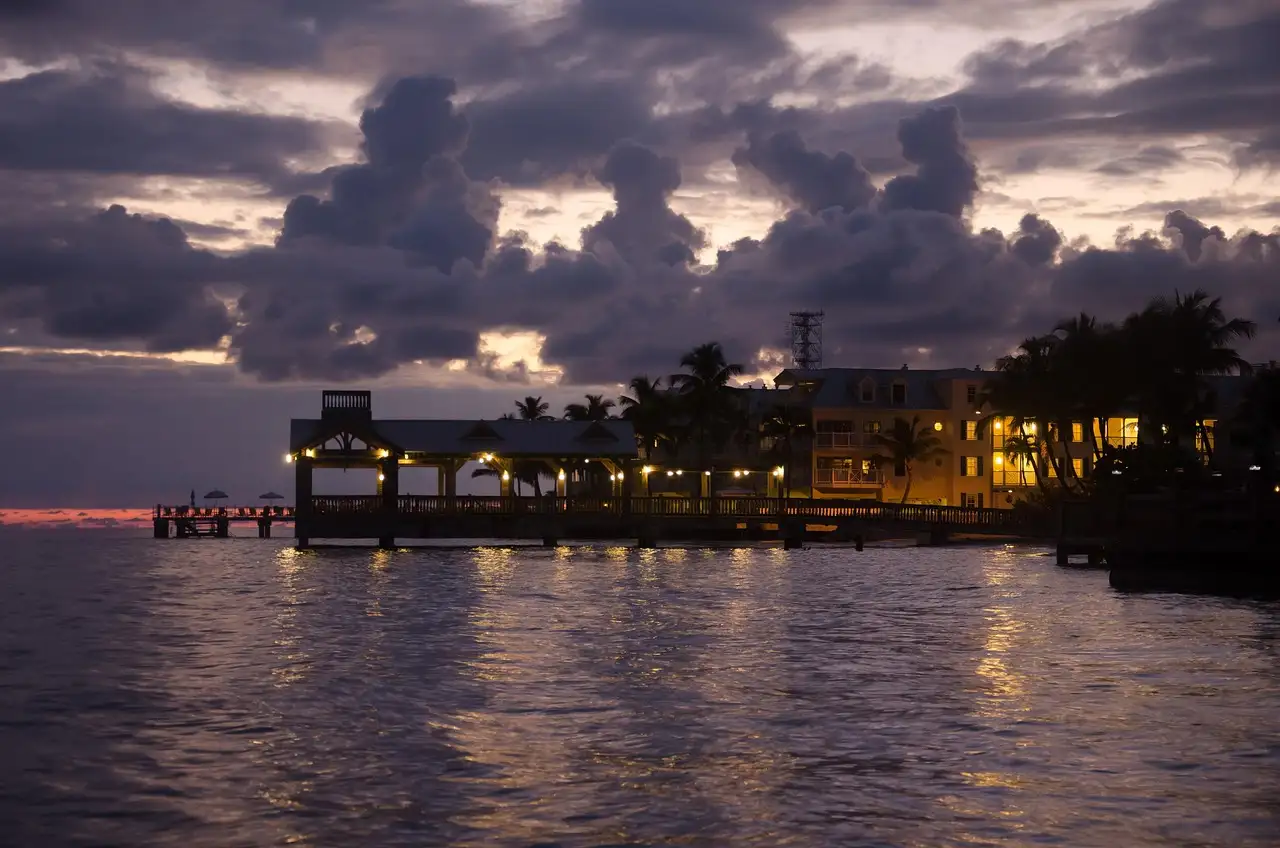 A Key West waterfront bar on a pier at dusk under heavy clouds