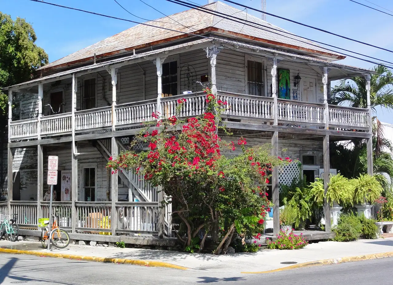 A two-storey wooden Key West house with porches and bougainvillea