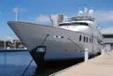 The bow of a large white yacht tied up at a dock