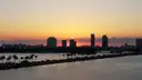 The Miami Beach skyline in silhouette at sunset across the water