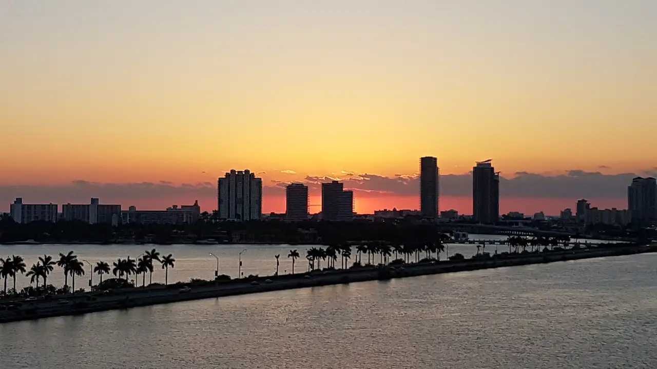 The Miami Beach skyline in silhouette at sunset across the water