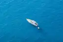 A white motor yacht on deep blue open sea, seen from above
