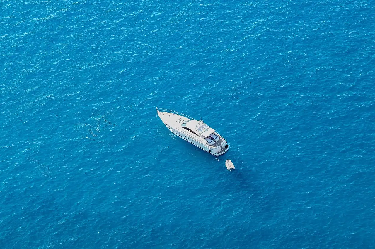 A white motor yacht on deep blue open sea, seen from above