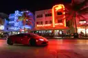 Ocean Drive at night, with neon-lit hotels and people at the outdoor tables