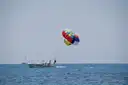 A parasail flying behind a tow boat on open sea