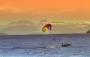 A parasail towed by a boat at golden hour