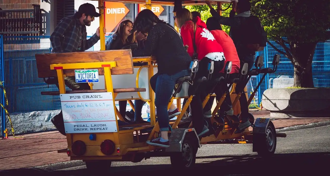 A group riding a pedal-powered bar bike down a street
