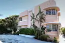 A pink Art Deco building with rounded corners and tropical plants in Miami Beach