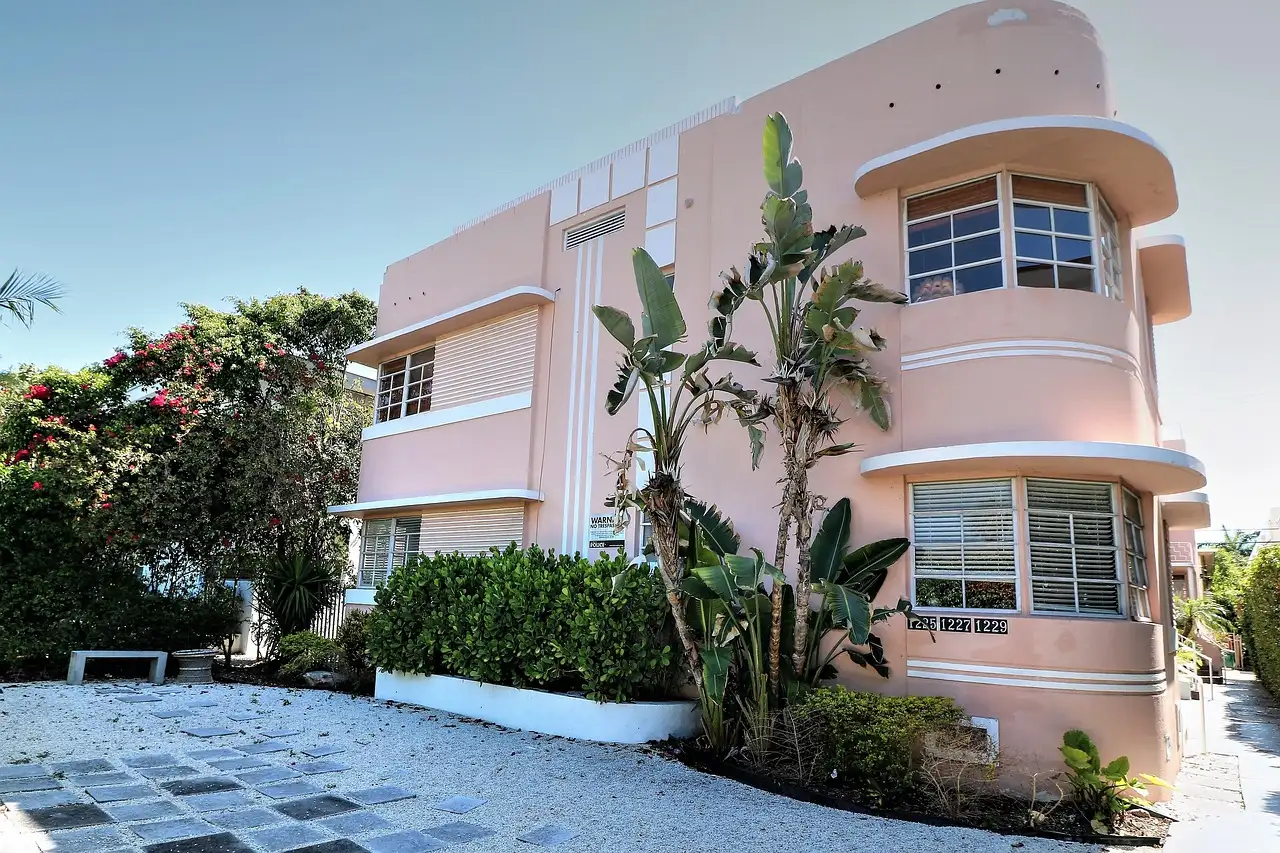 A pink Art Deco building with rounded corners and tropical plants in Miami Beach