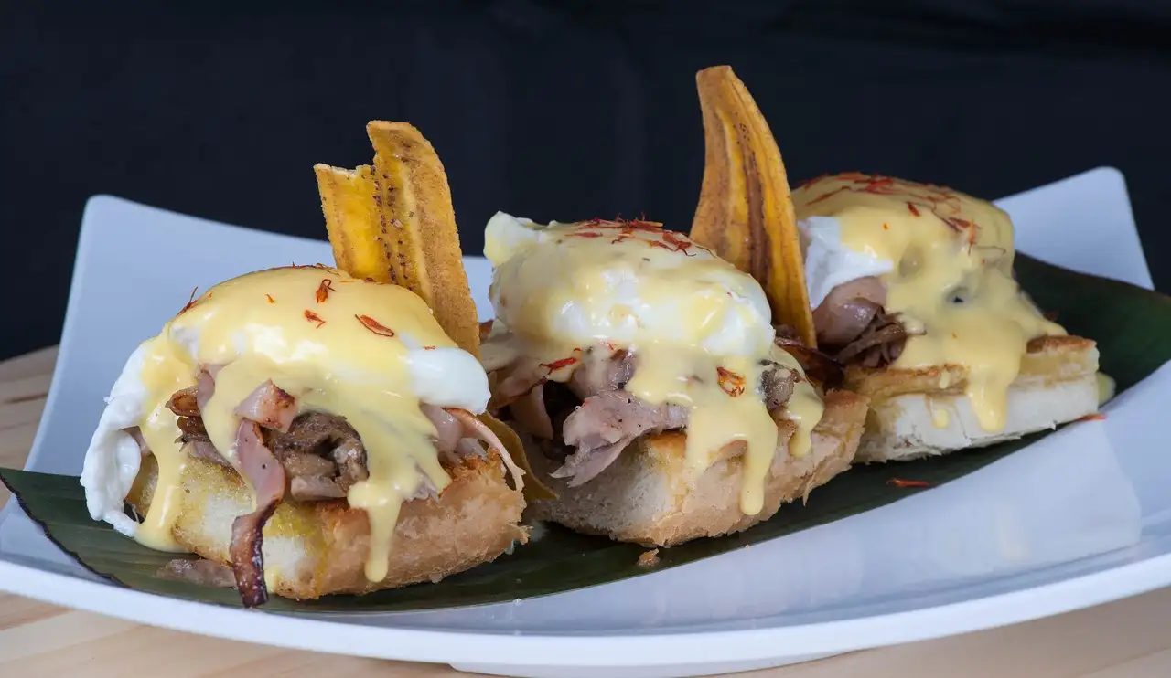 Toasted bread topped with pulled meat, sauce and fried plantain chips