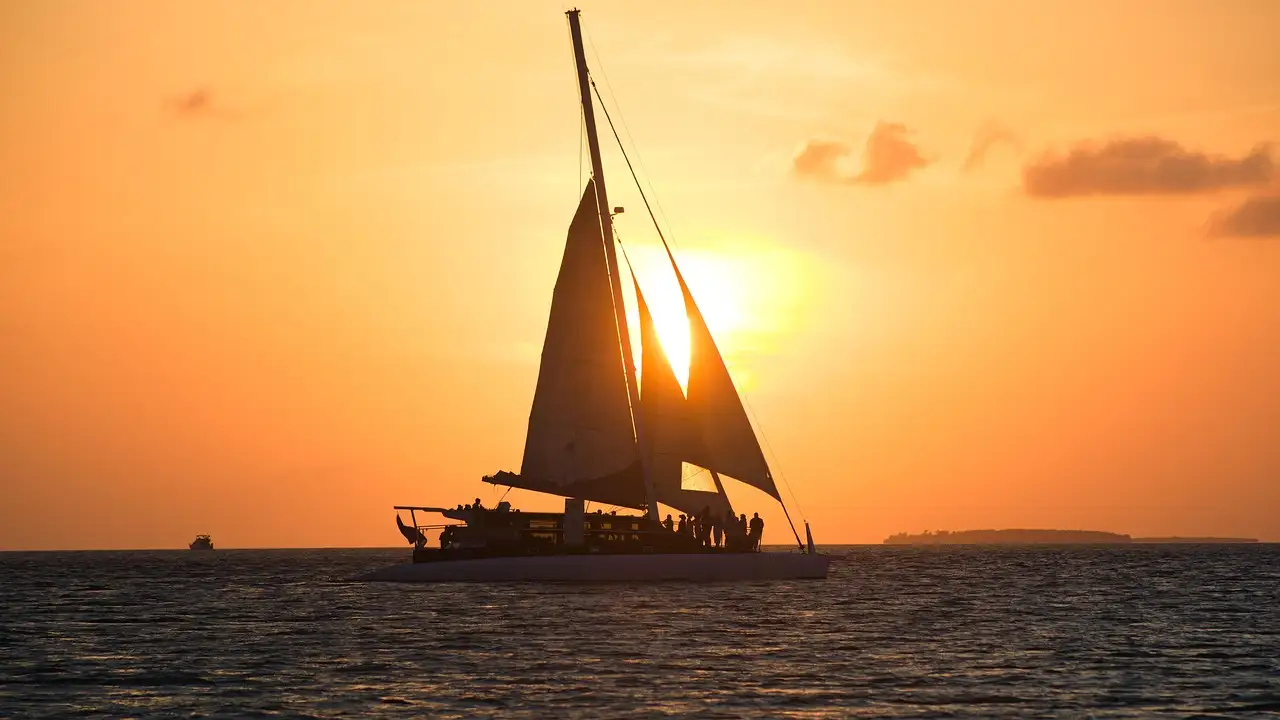 A sailing catamaran in silhouette against a Key West sunset