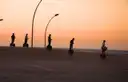 Segway riders in silhouette on a seaside promenade at sunset