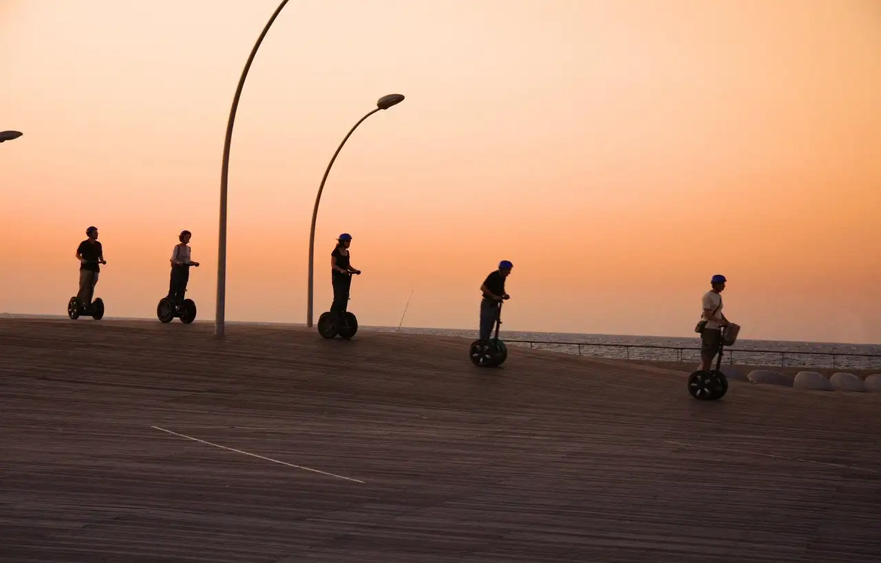 Segway riders in silhouette on a seaside promenade at sunset