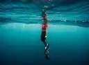 A snorkeler in clear blue water seen from below