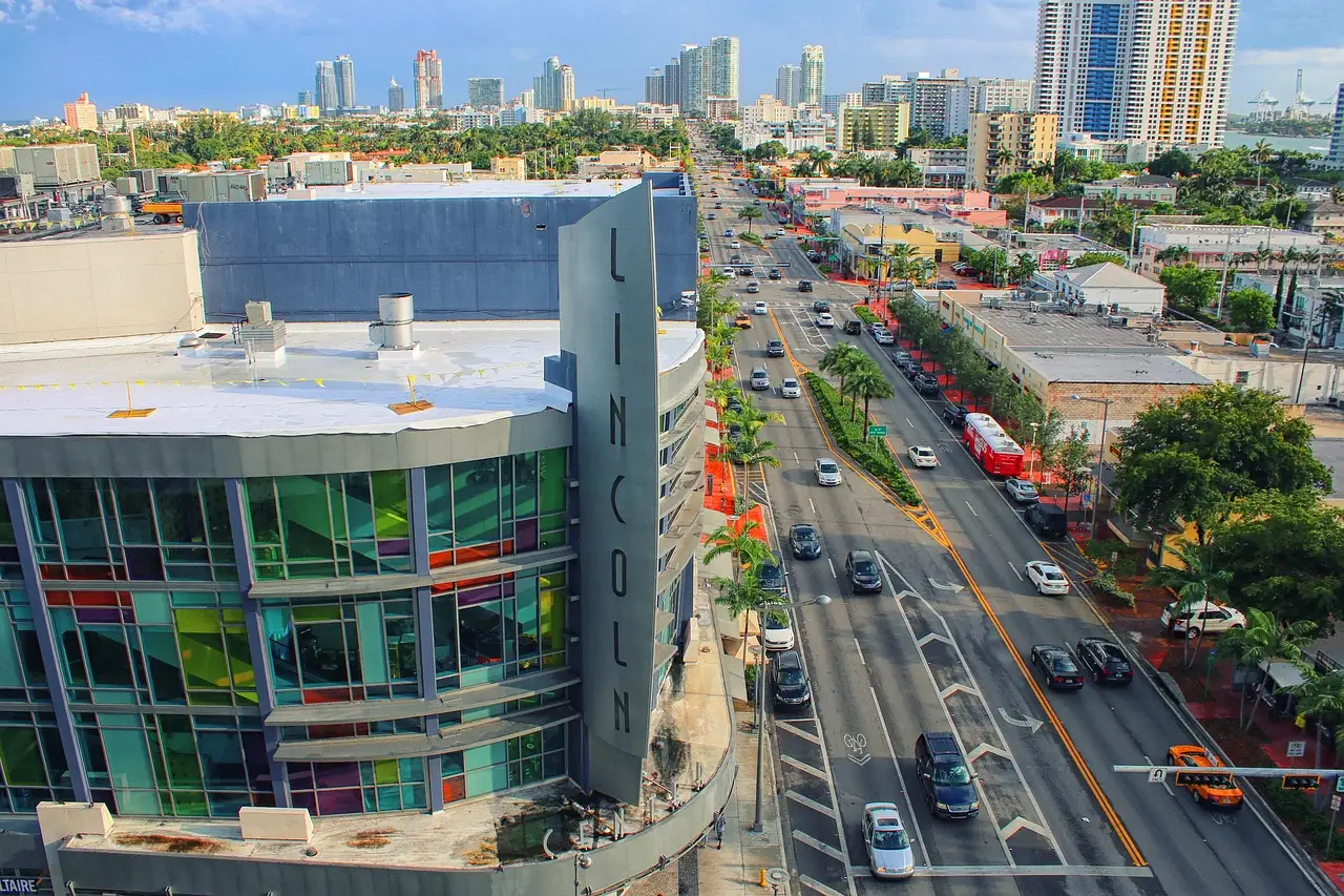 Aerial view of a busy sunlit street in Miami Beach with traffic and shops