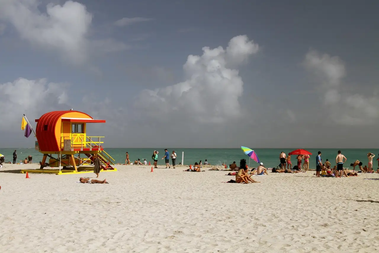 Red lifeguard hut on a sunny Miami beach under scattered clouds