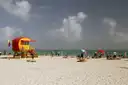 Red lifeguard hut on a sunny Miami beach under scattered clouds