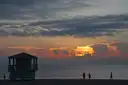 Couples walking on Miami Beach at sunset beside a lifeguard tower